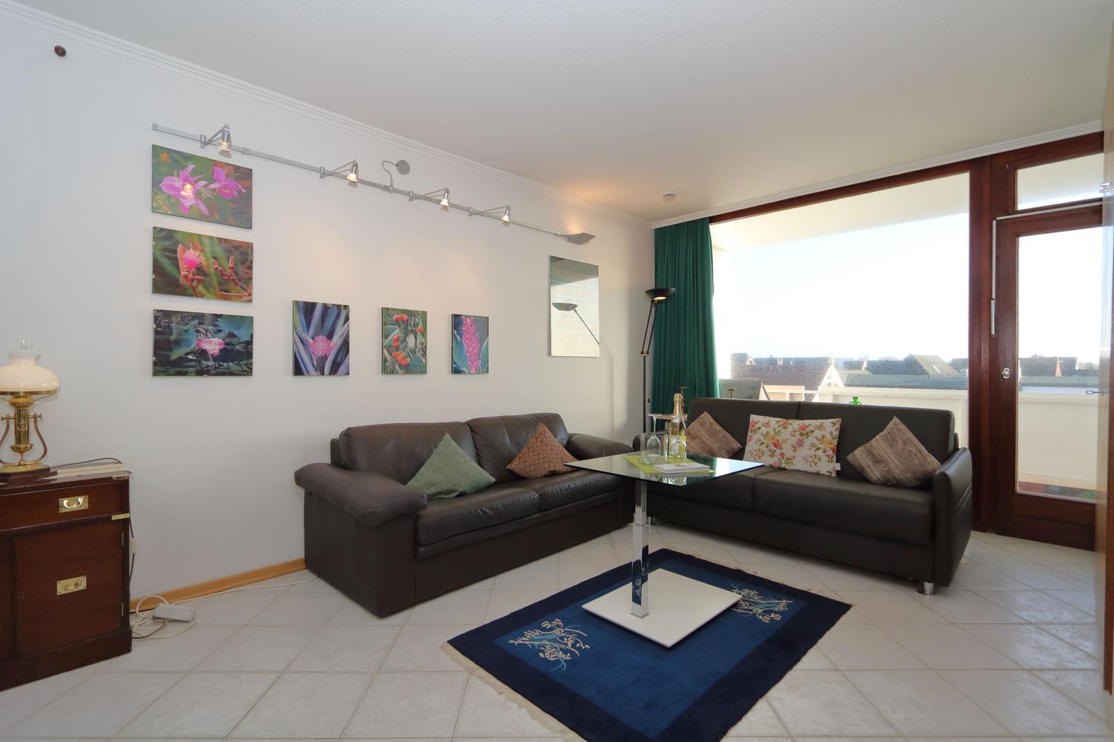 Living room with two sofas, glass table, and balcony view.