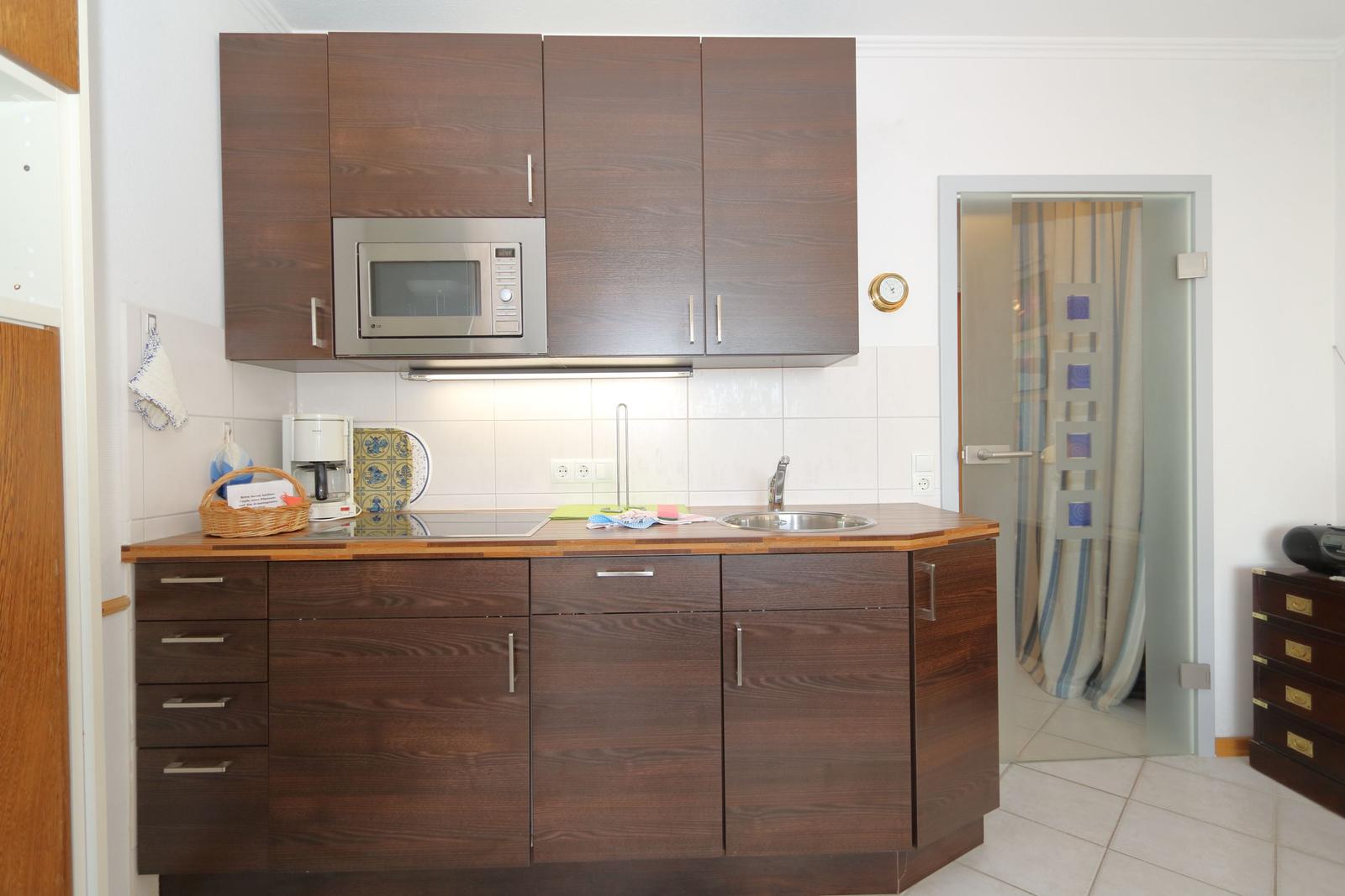 Kitchen with wooden cabinets, microwave, and sink