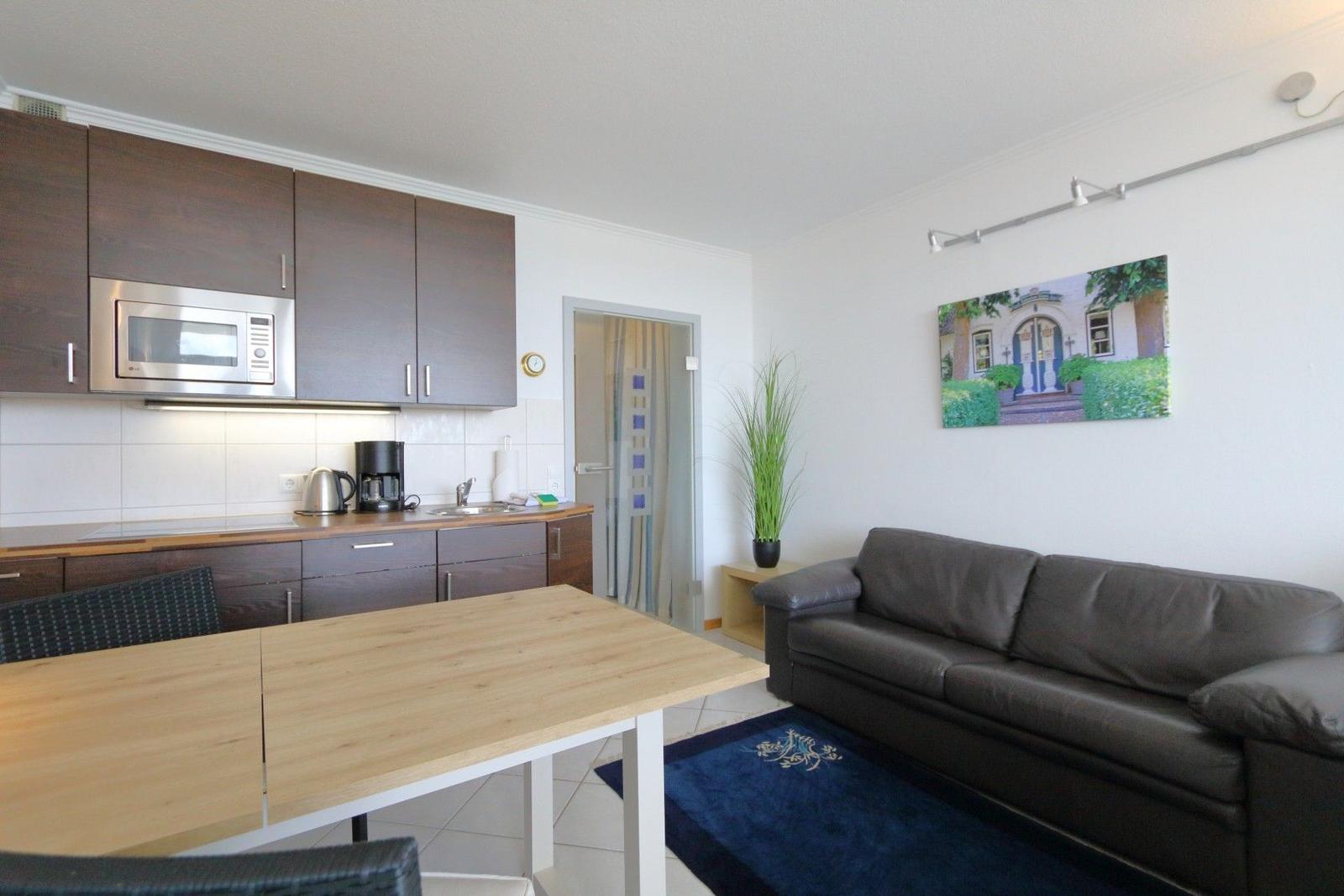 Living area with sofa, dining table, and kitchenette with microwave.