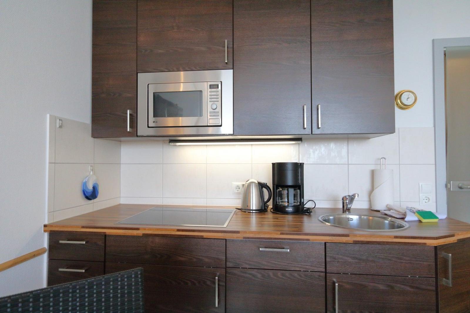 Kitchen with dark cabinets, microwave, coffee machine, and sink.