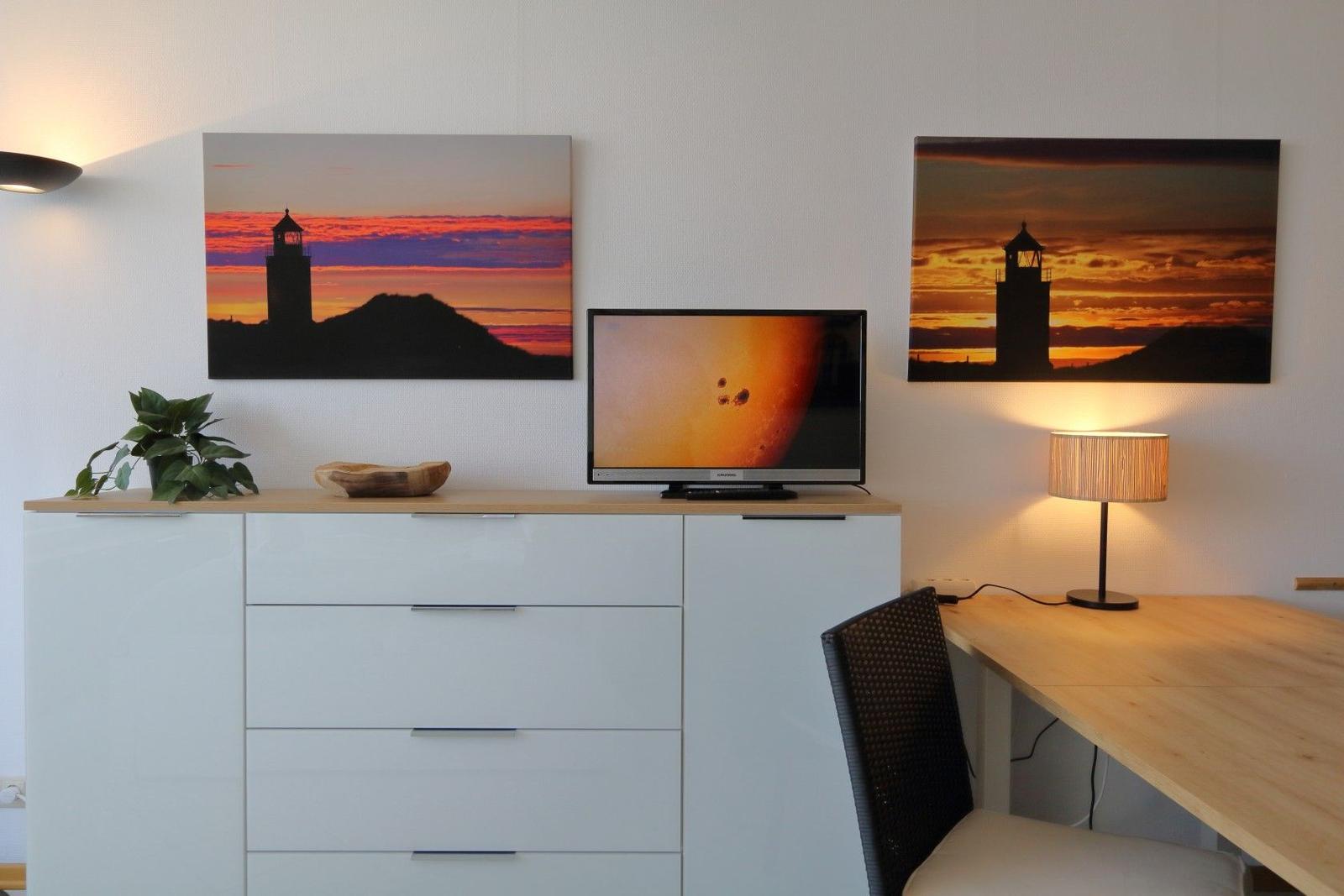 Desk area with TV, two wall pictures, and a lamp.