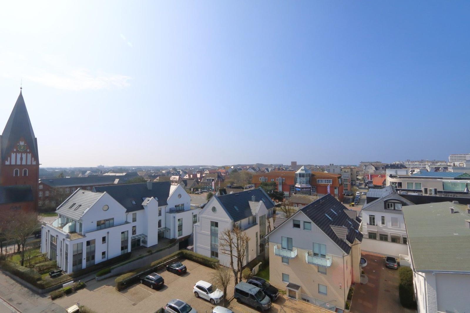 Panoramablick auf moderne Häuser und eine Kirche unter blauem Himmel.