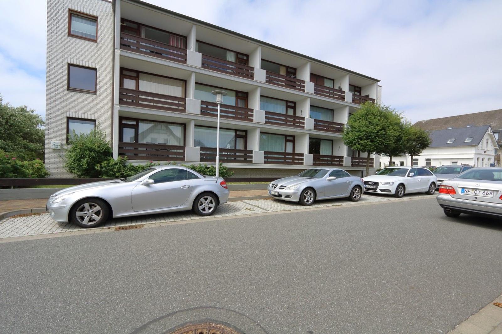 Villa with balconies and parked cars in front