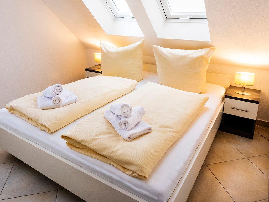 Schlafzimmer mit Doppelbett, zwei Nachttischen und Dachfenstern.