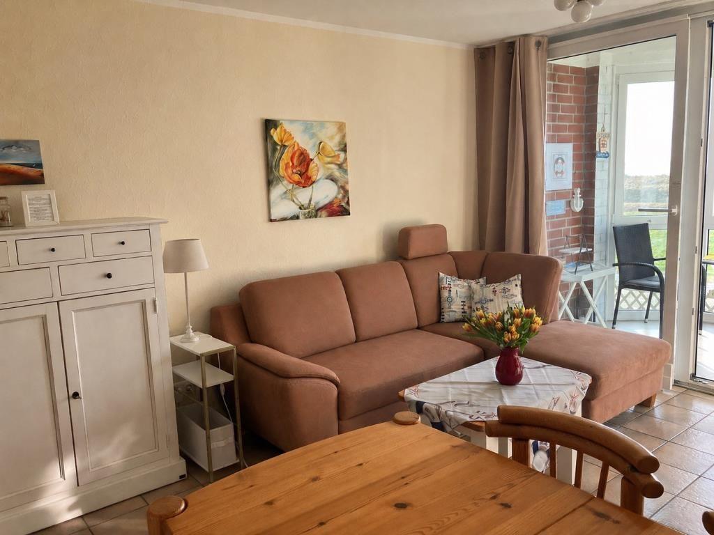 Wohnzimmer mit braunem Sofa, Esstisch und Blick auf Balkon.