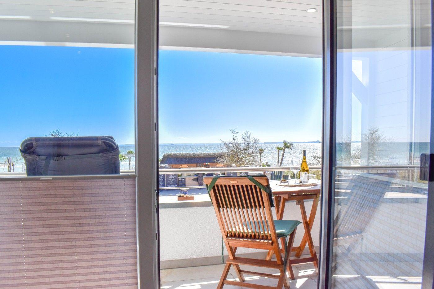 Terrasse mit Tisch und Stuhl, Blick auf Meer und Strand.