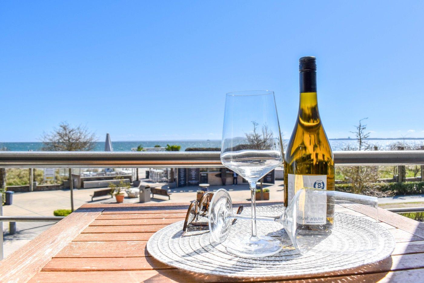 Weinflasche und Glas auf Balkon mit Meerblick