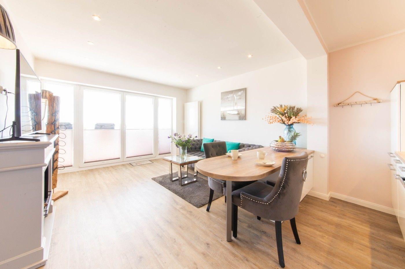 Wohn- und Essbereich mit Holzboden, Sofa, Esstisch und Fenster zur Terrasse.