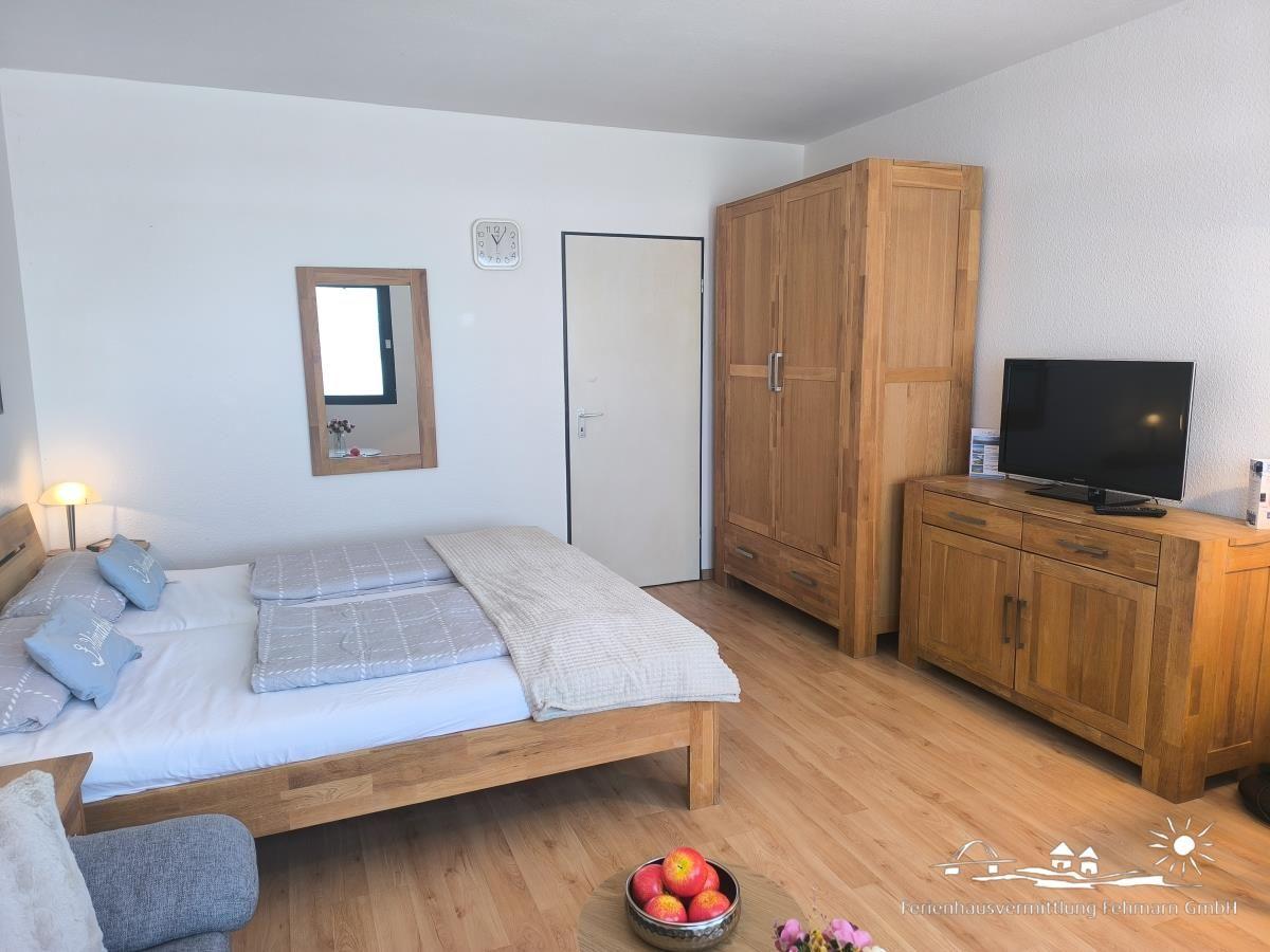 Schlafzimmer mit Holzbett, Kleiderschrank und Fernseher.