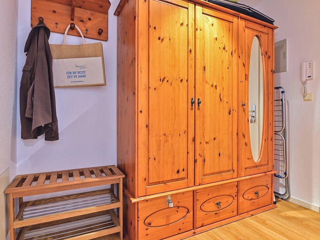 Holzschrank mit Spiegeltür und Schubladen, Wandgarderobe und Kleiderständer im Flur.