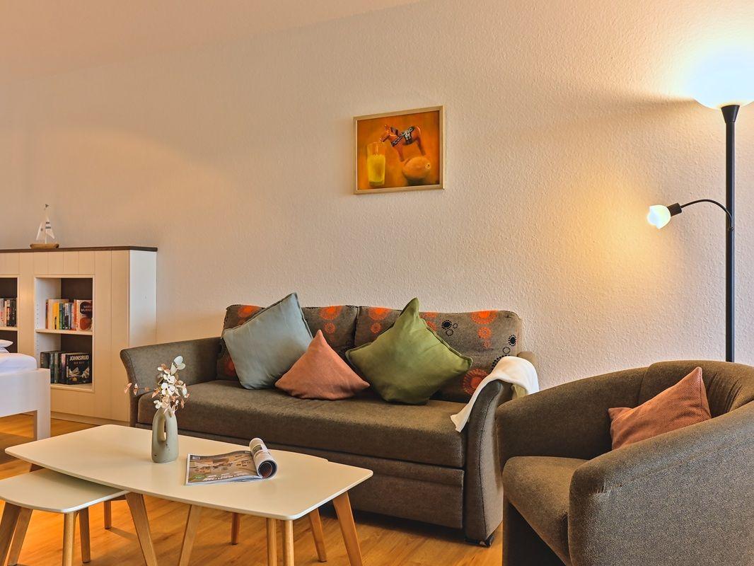 Wohnzimmer mit Sofa, Sessel, Tisch und Wandbild.