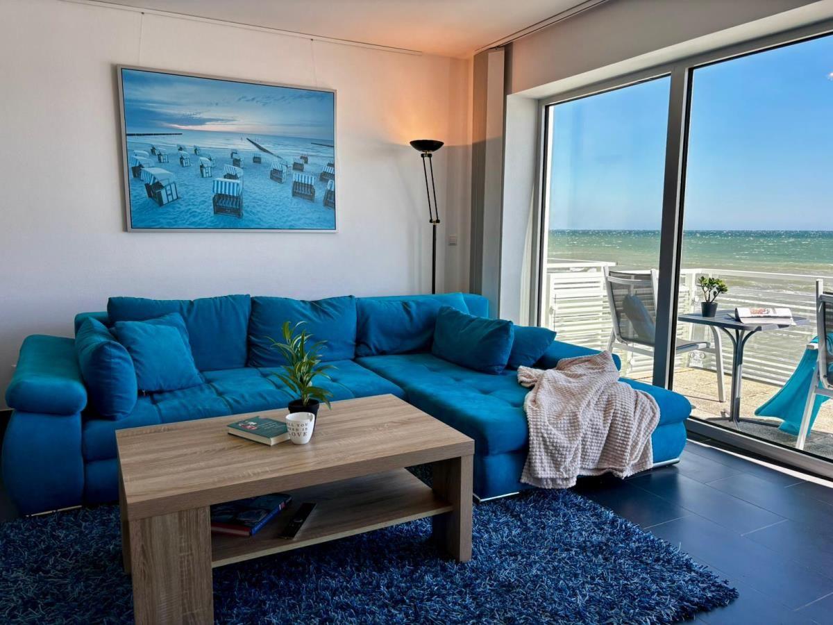 Blauer Sofa im Wohnzimmer mit Meerblick durch Glasfront.