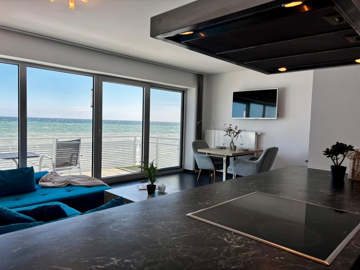Küche mit Blick aufs Meer. Essbereich und Wohnbereich mit blauem Sofa.