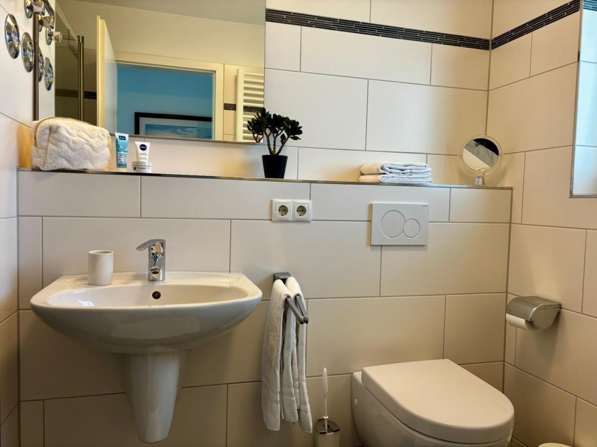 Badezimmer mit Waschbecken, Spiegel, Toilette und Handtuchhalter.