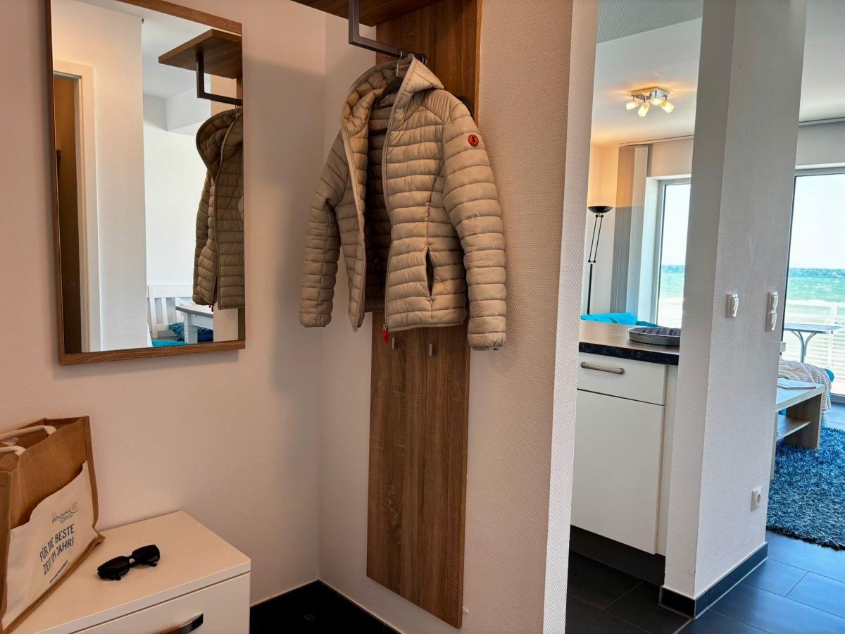 Hängende Jacke neben Spiegel und Blick in Küche mit Küchenzeile und Blick auf Meer.