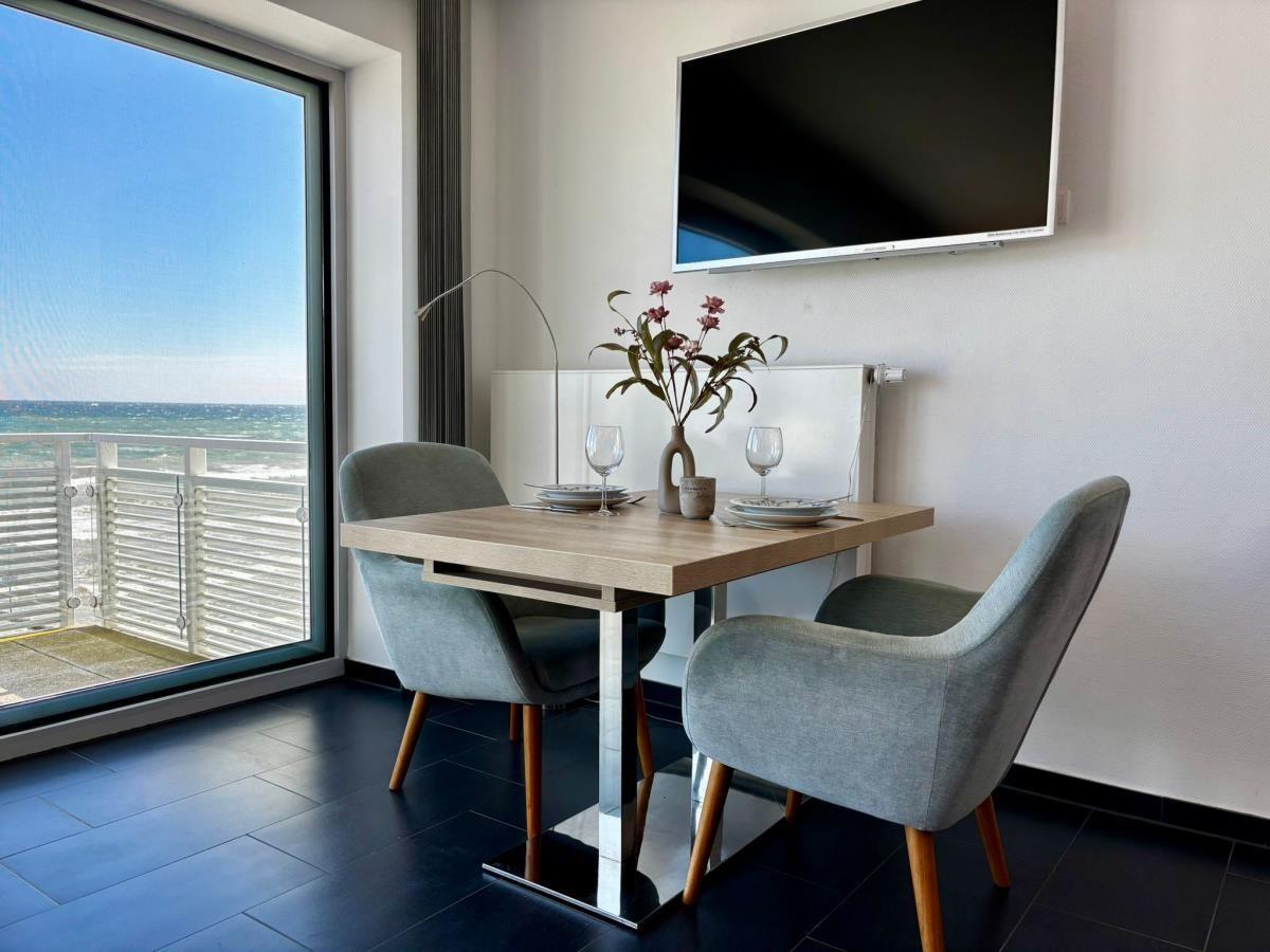 Esstisch mit zwei Stühlen und TV. Große Fensterfront mit Meerblick.