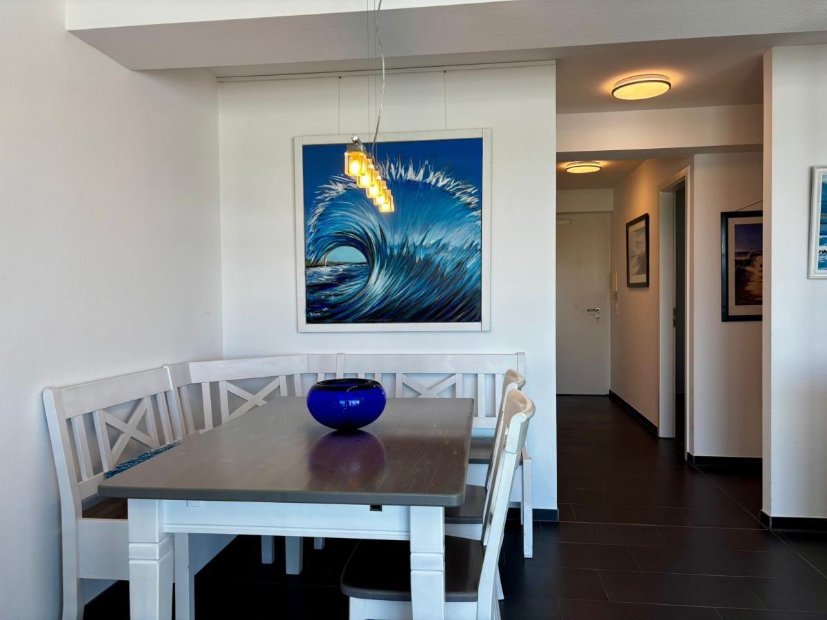 Esszimmer mit Tisch, Stühlen und Wandbild einer Welle.