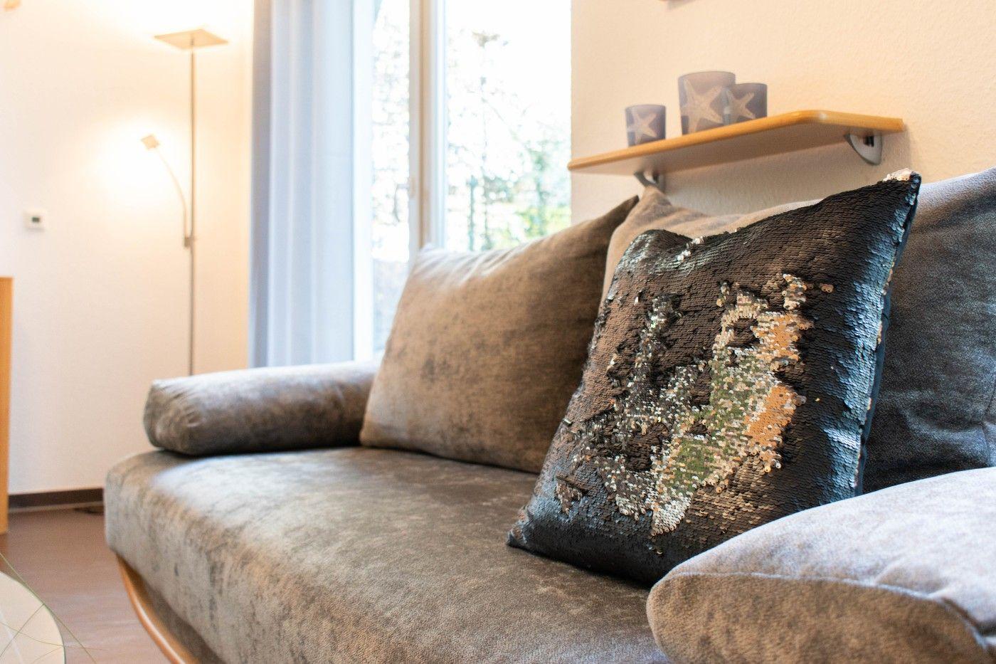 Ein Sofa mit Kissen und einem Wandregal mit Vasen.