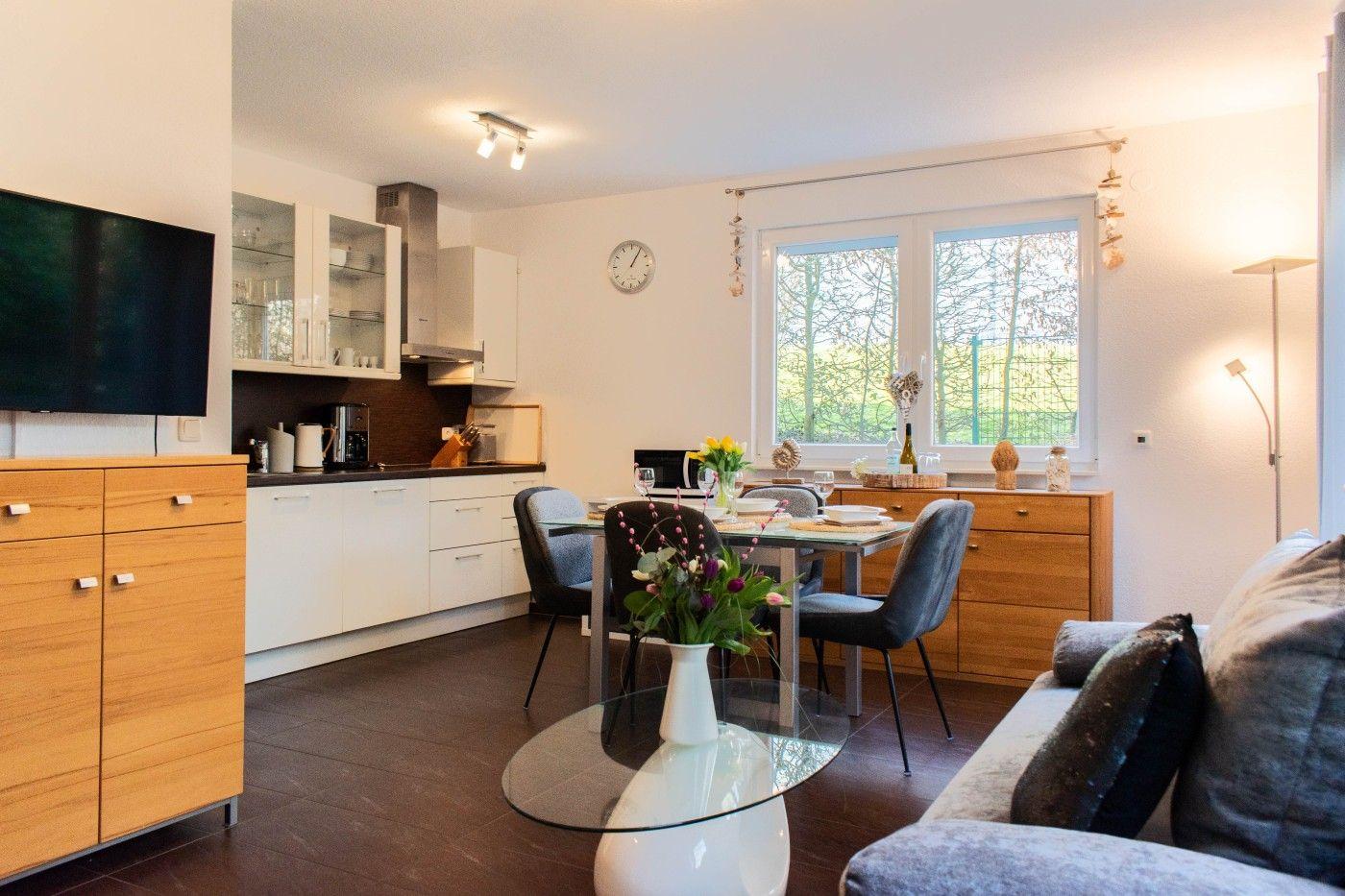 Wohnküche mit Essbereich, TV, Fenster und moderner Einrichtung.