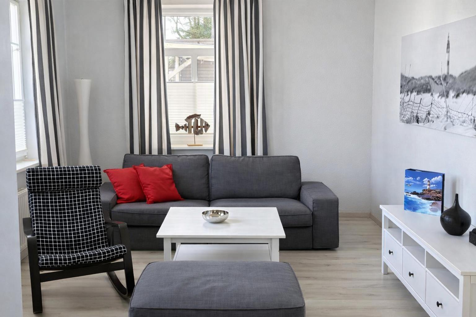 A living room with a gray sofa, red cushions, and a white coffee table.