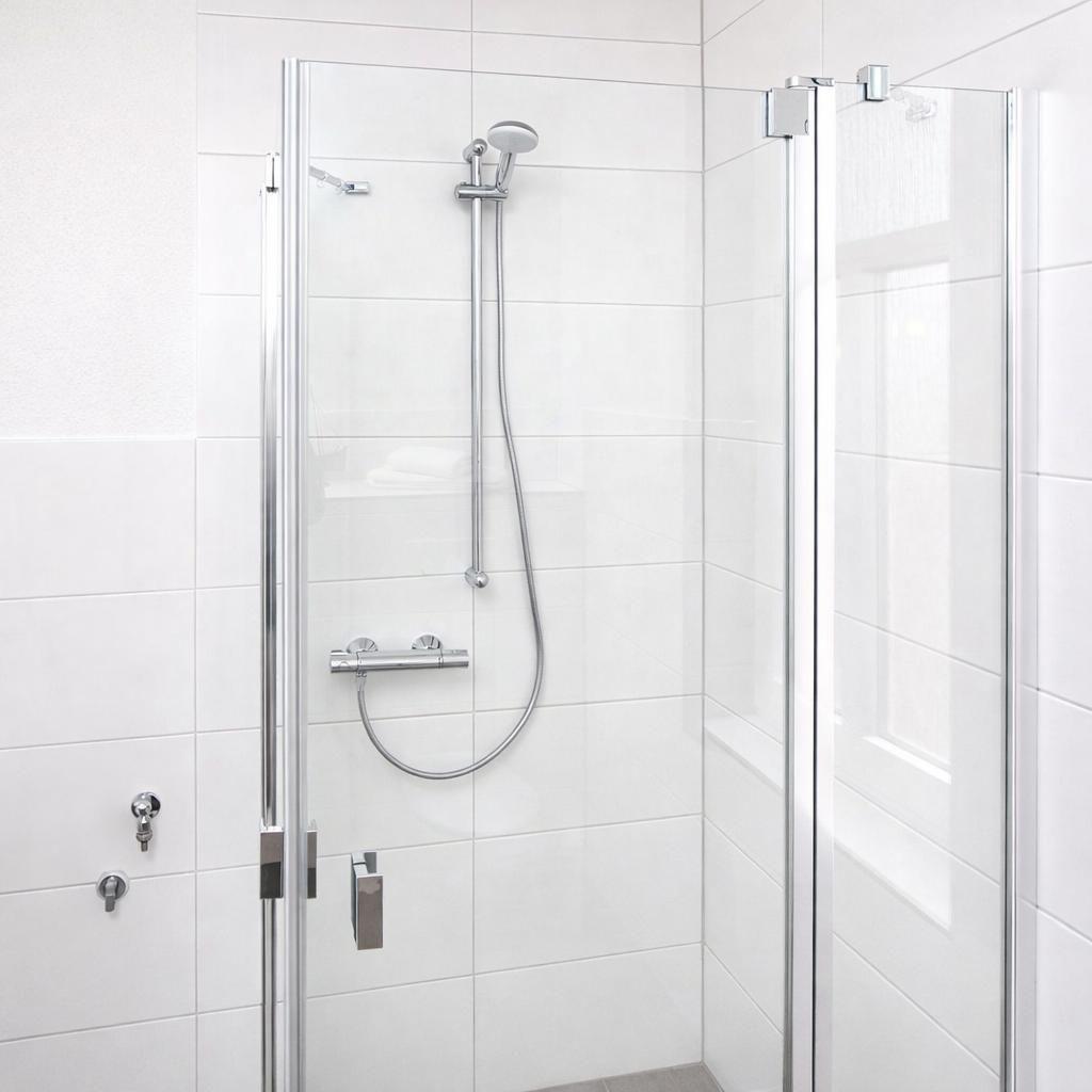 Shower cabin with glass door and shower head on the wall