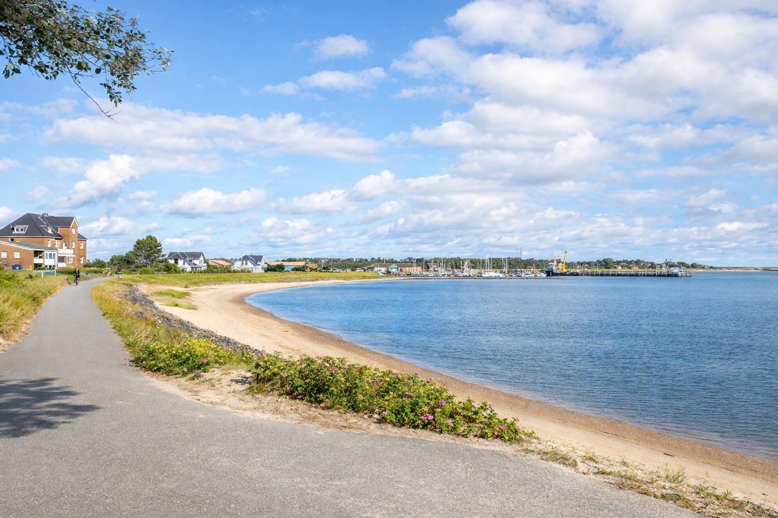 Path along the beach with view of harbor and houses.