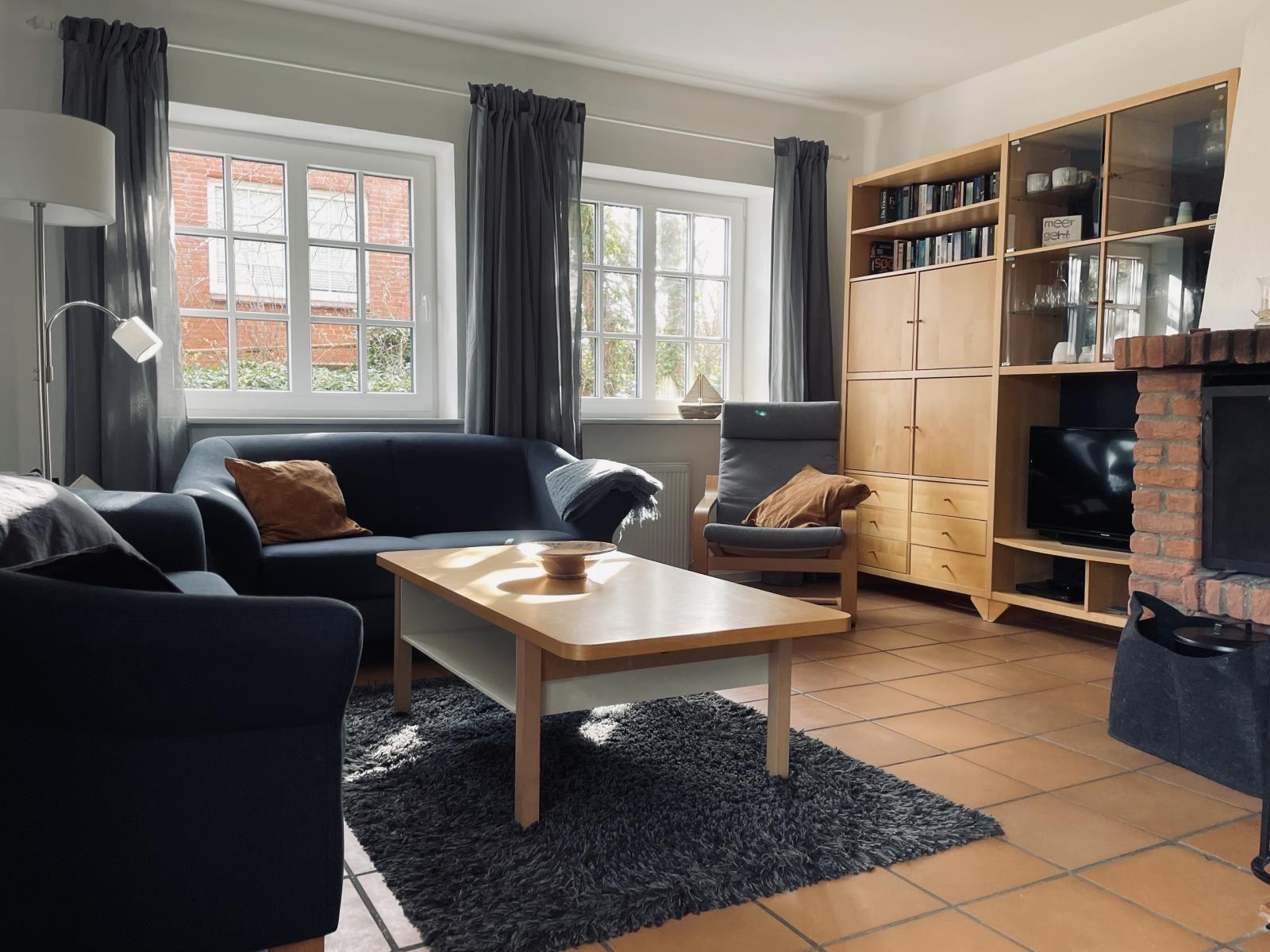 Wohnzimmer mit Sofa, Sessel, Couchtisch und Kamin