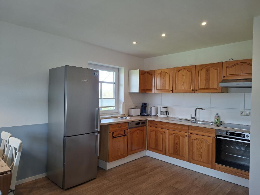Küche mit Holzschränken, Kühlschrank und Kochfeld.
