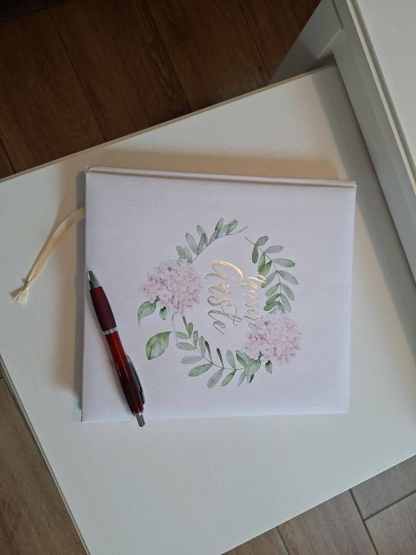 Ein Buch mit Blumenmotiv liegt auf einem Tisch neben einer roten Kugelschreiber.