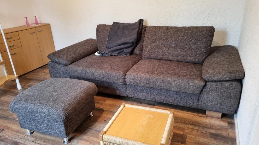 A sofa with footstool and coffee table on wooden floor.