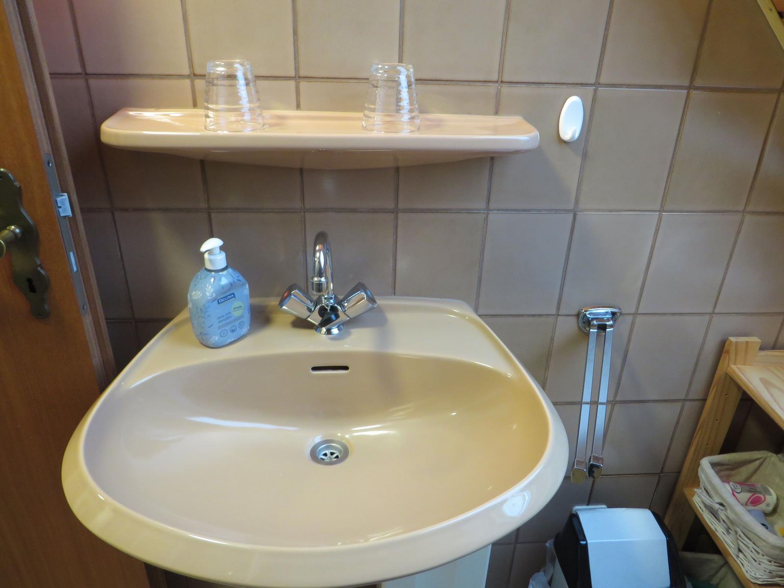 Waschbecken mit Spiegel, Seife und Handtuchhalter an der Wand