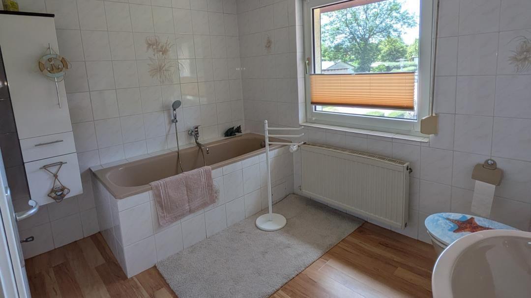 Bad mit Badewanne, Fenster, Heizkörper und Toilette