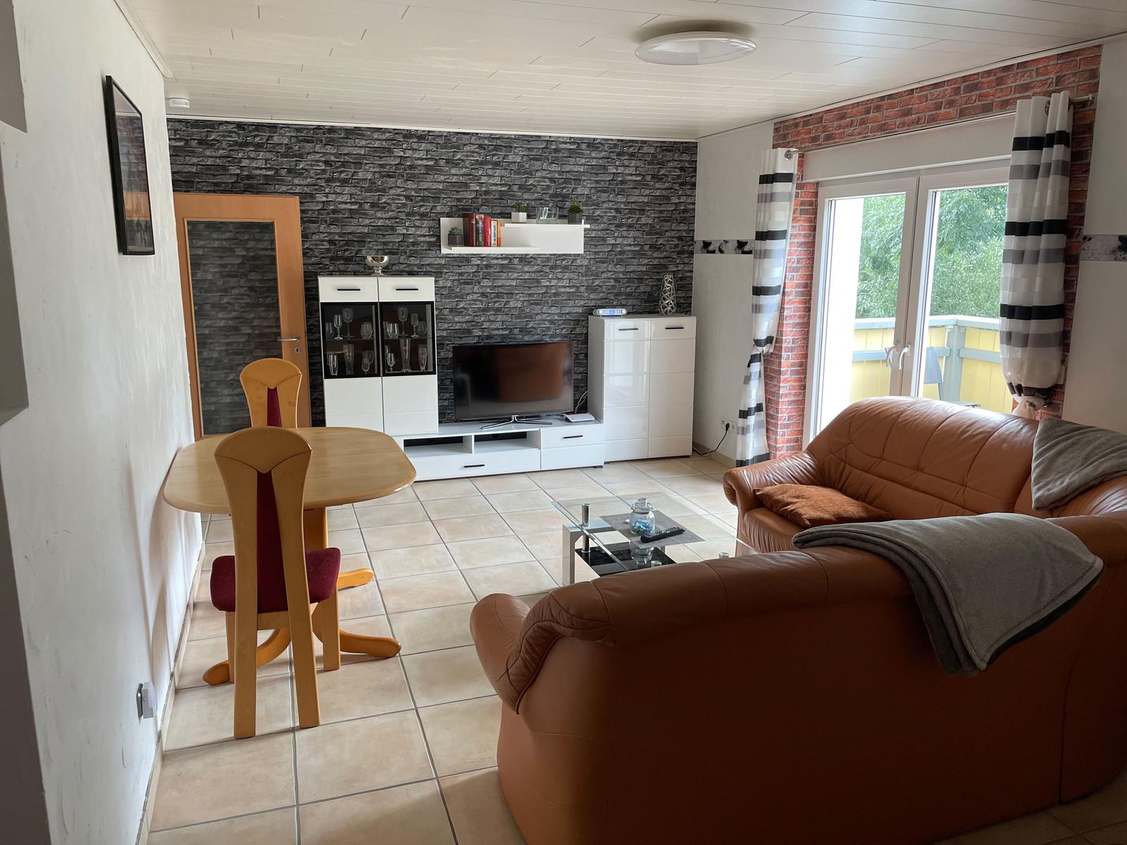 Living and dining area with brown sofa, dining table, and TV.
