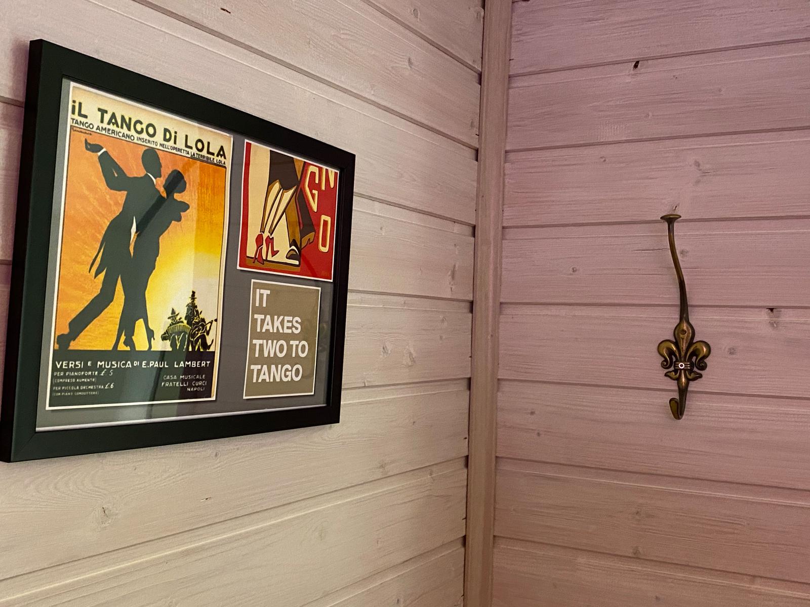 Wand mit gerahmtem Tango-Poster und messingfarbenem Haken