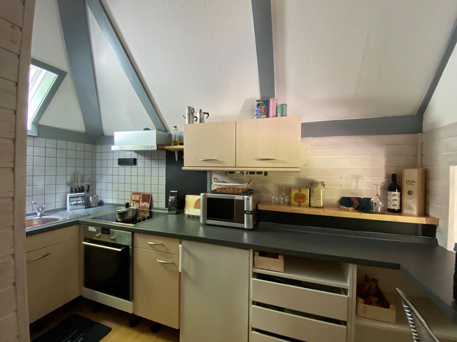 Küche mit Dunstabzug, Mikrowelle und Spüle unter schrägem Dach
