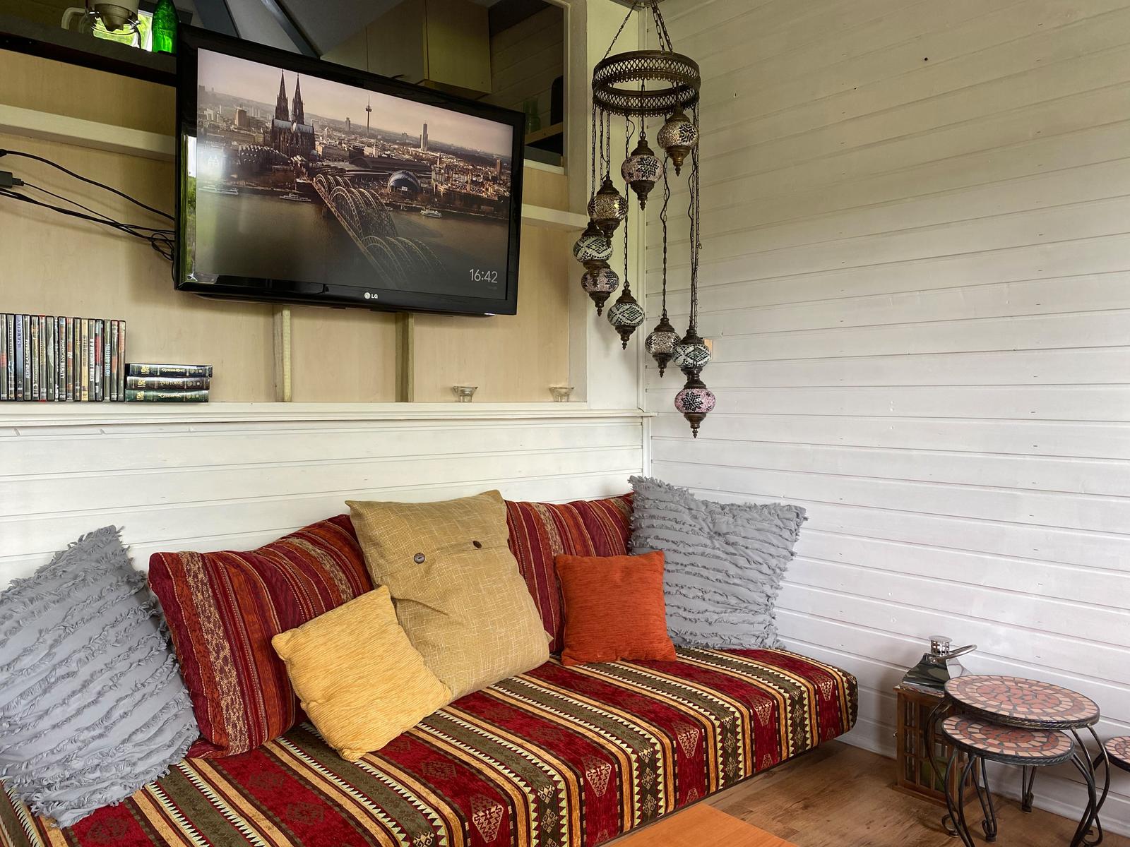 Ein Sofa mit Kissen, Fernseher und Hängelampen an der Wand.