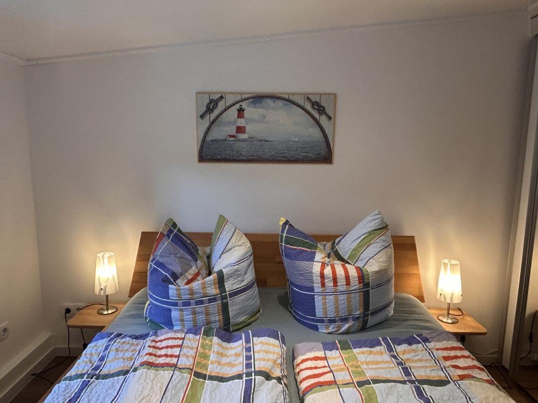 Schlafzimmer mit Bett, zwei Nachttischen und einer Wanddekoration mit Leuchtturm.