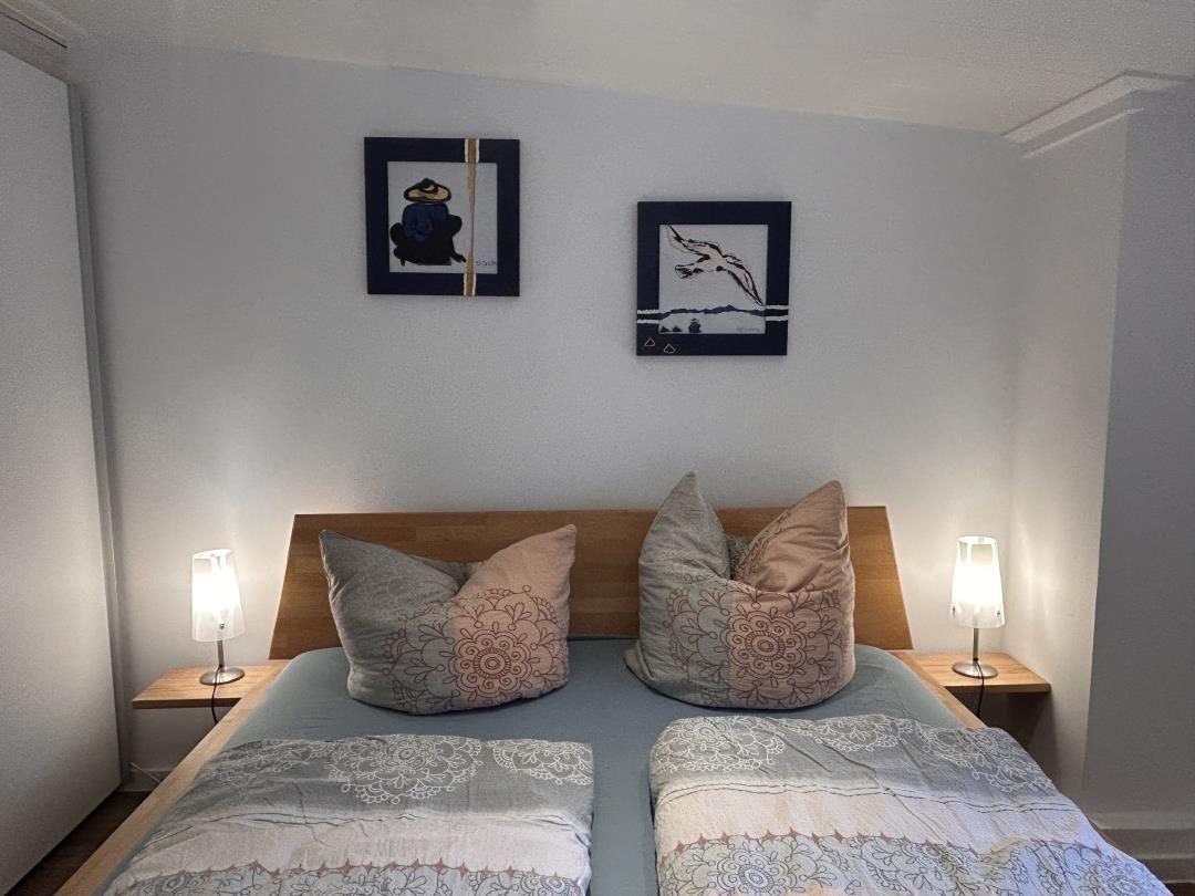 Ein Schlafzimmer mit Doppelbett, zwei Nachttischen und zwei Bildern an der Wand.
