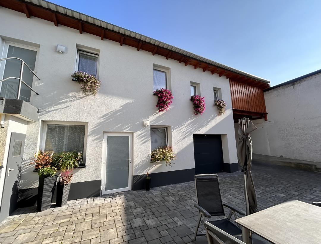 Haus mit Terrasse, Blumenkästen und Gartenmöbeln im Freien.