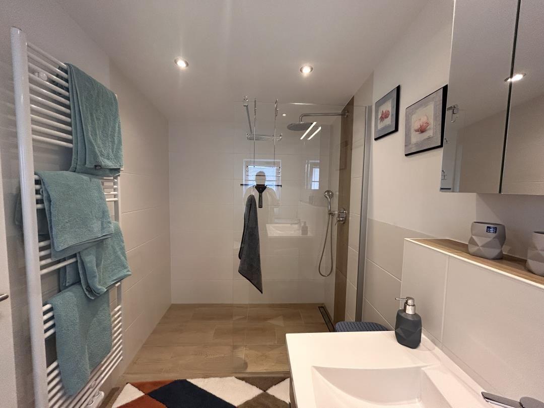 Bad mit Dusche, Waschbecken und Heizung für Handtücher.