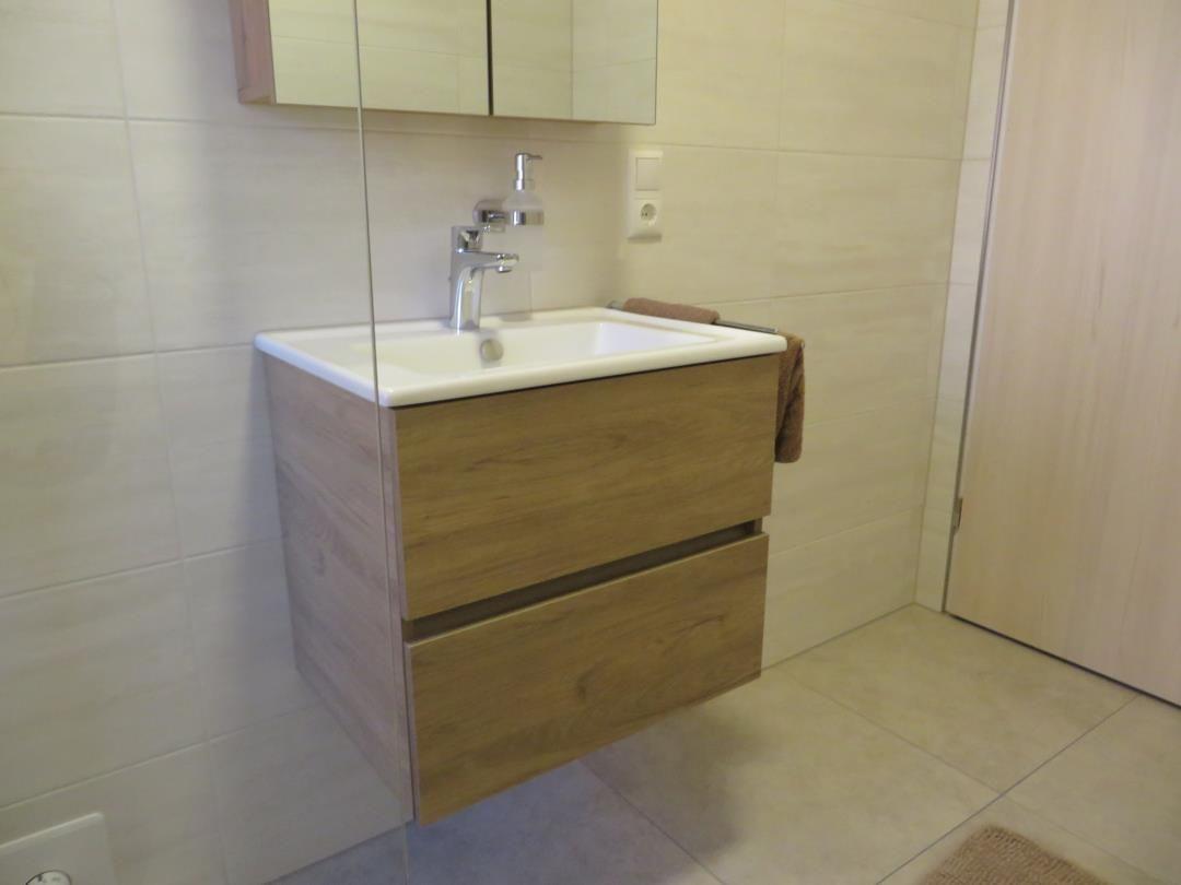 Hängendes Waschbecken mit Spiegelschrank und Handtuchhalter an der Wand.