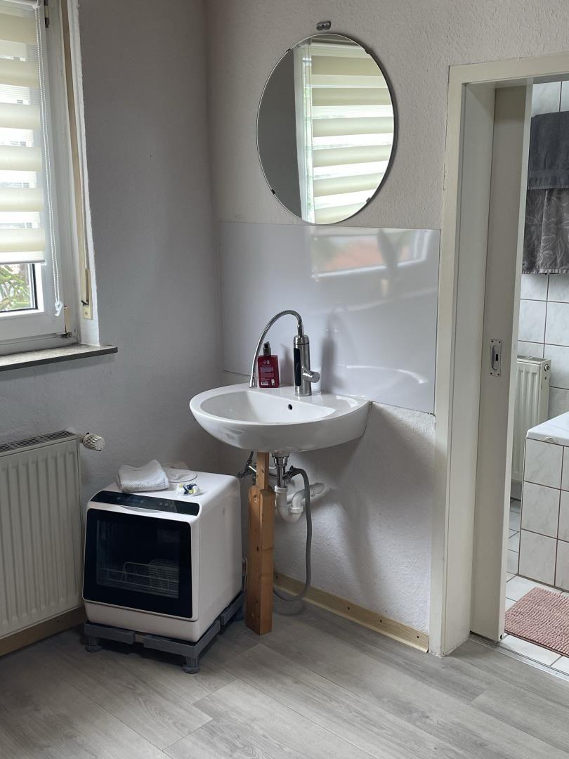 Badezimmer mit Waschbecken, Spiegel und Waschmaschine.