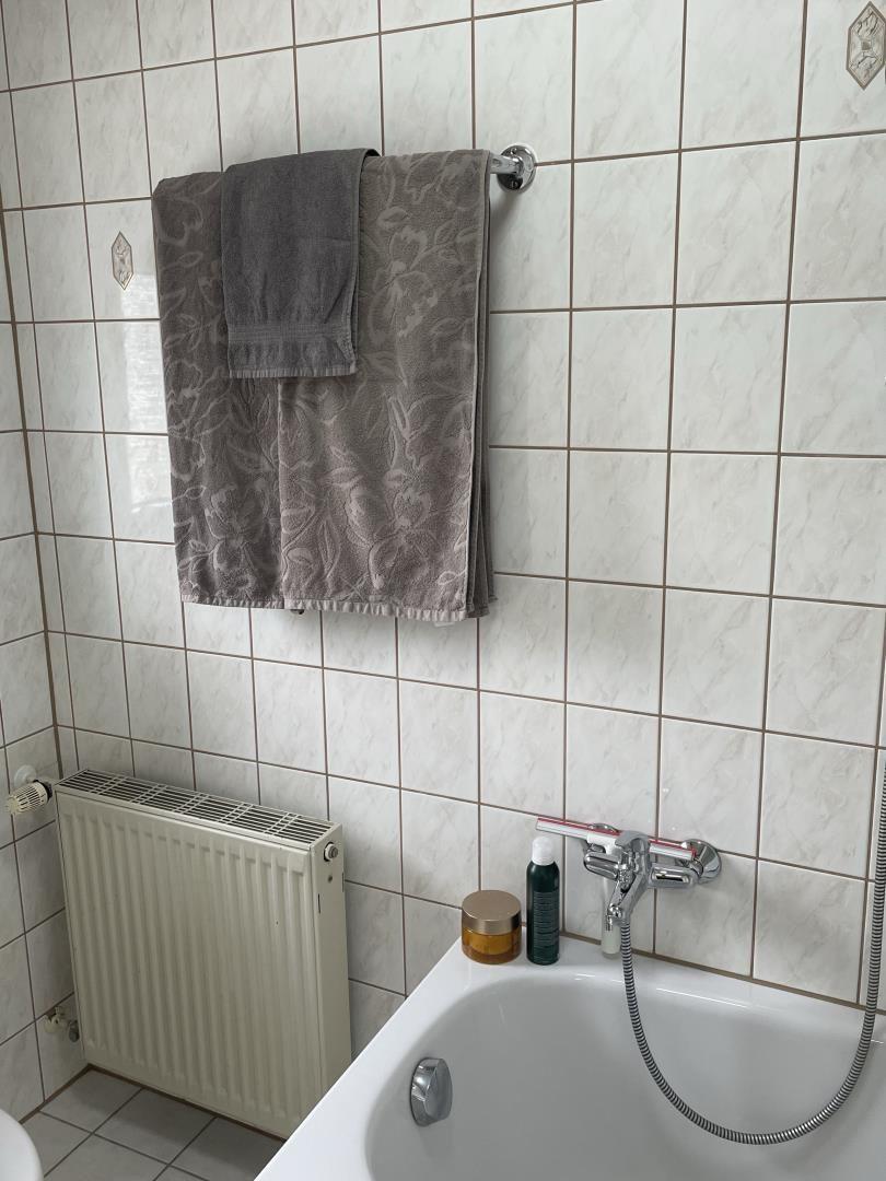 Bad mit Dusche, Handtuchhalter und Heizkörper an Wand