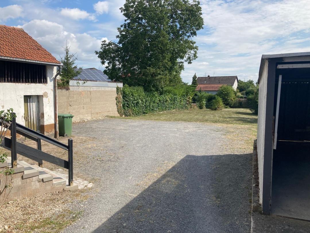 Gepflasterter Hof mit Garage, Stall und Garten. Hinterhof mit Bäumen und Mauer.