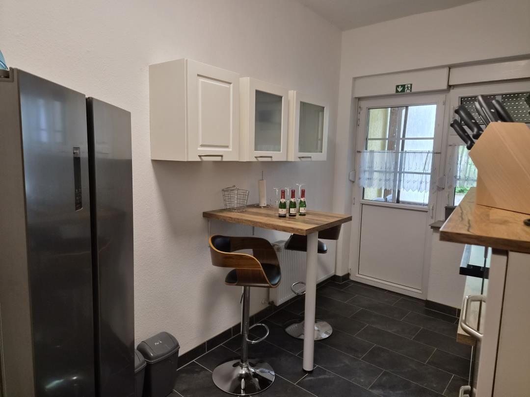 Küche mit Barhocker, Kühlschrank und Fenster zur Außentür.