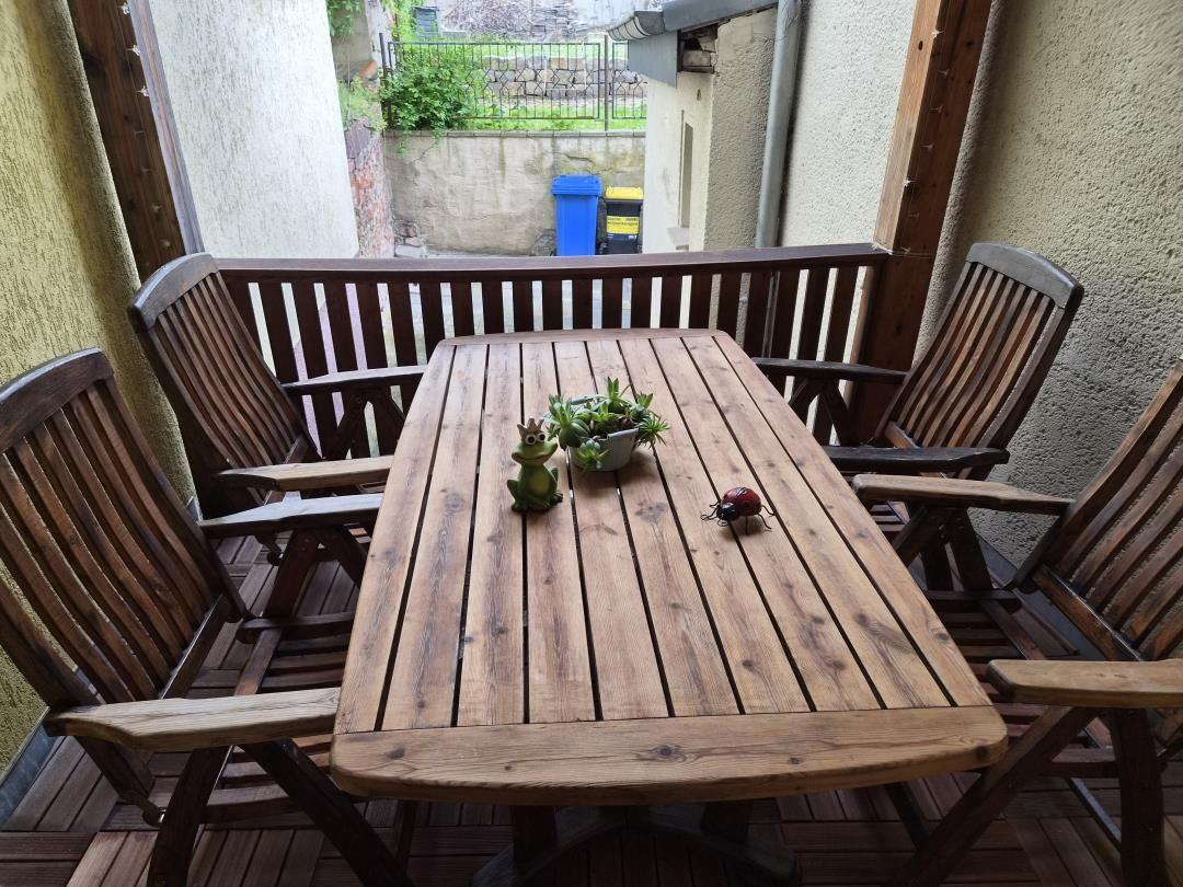 Holztisch mit vier Stühlen auf Terrasse. Tisch mit Pflanze und Dekoration.