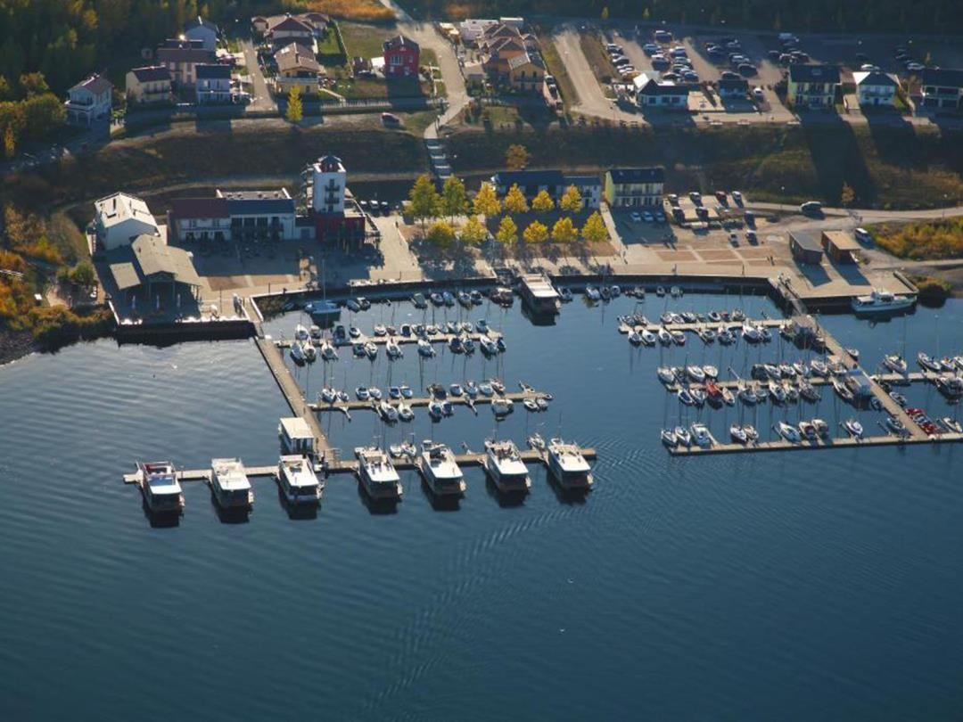 Hafen mit Booten und angrenzenden Gebäuden in einer ländlichen Umgebung.