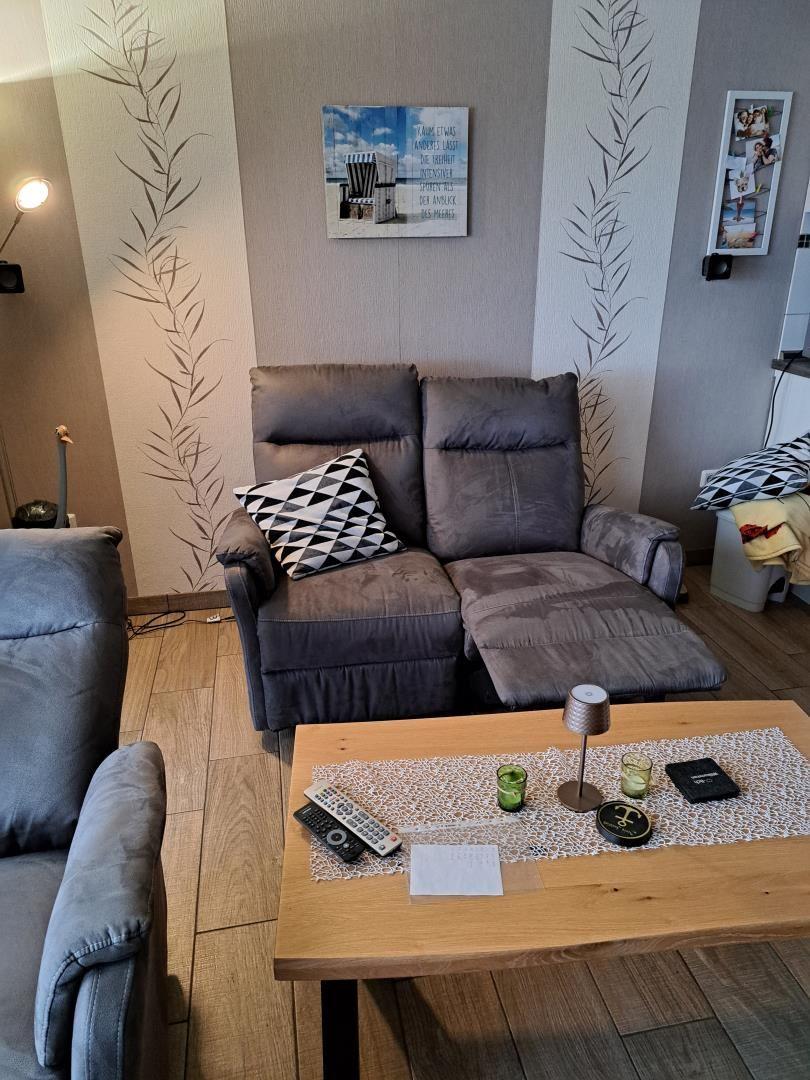 Ein Wohnzimmer mit grauem Sofa, Holztisch und Wandbildern.
