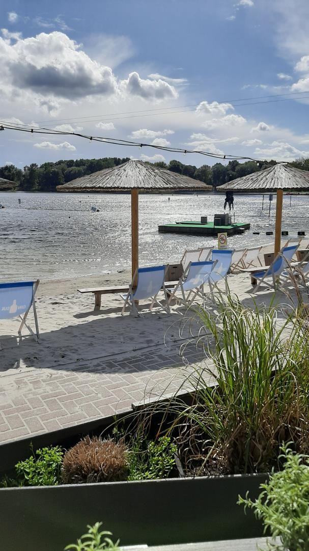Strand mit Liegestühlen, Sonnenschirmen und Blick aufs Wasser.