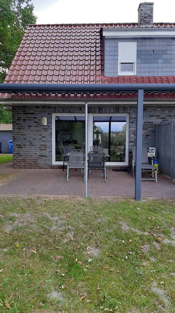 Haus mit Terrasse, Garten und Sitzgelegenheiten. Fenster und Dach sichtbar.